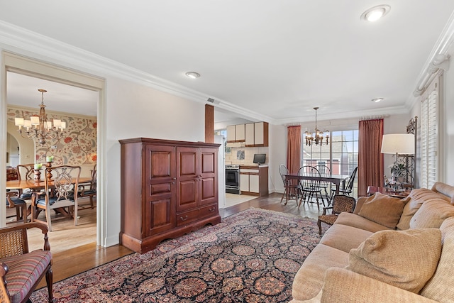 living room featuring ornamental molding, light wood-type flooring, and an inviting chandelier