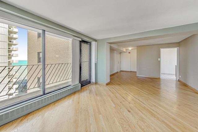 unfurnished room featuring a baseboard radiator and light wood-type flooring