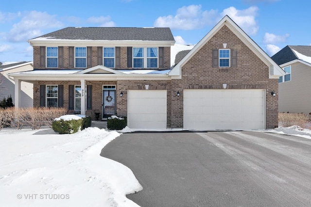 view of front facade with a garage, brick siding, and aphalt driveway