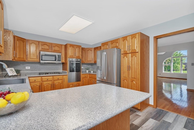 kitchen featuring light wood-type flooring, appliances with stainless steel finishes, sink, and backsplash