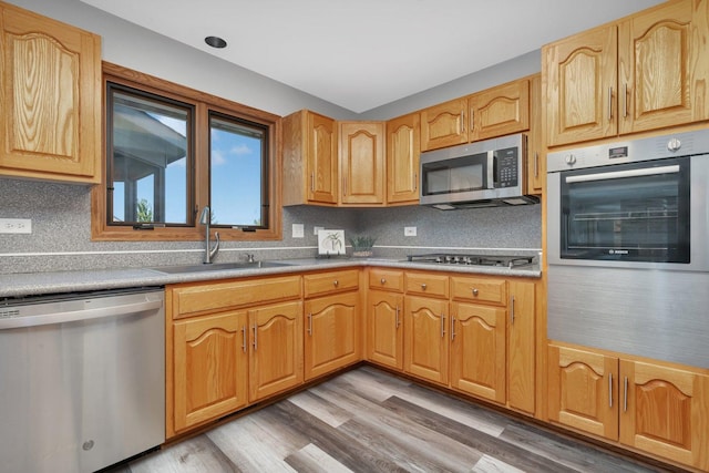 kitchen featuring sink, hardwood / wood-style flooring, stainless steel appliances, and decorative backsplash