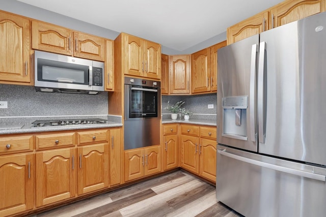 kitchen with stainless steel appliances, light wood-type flooring, and decorative backsplash