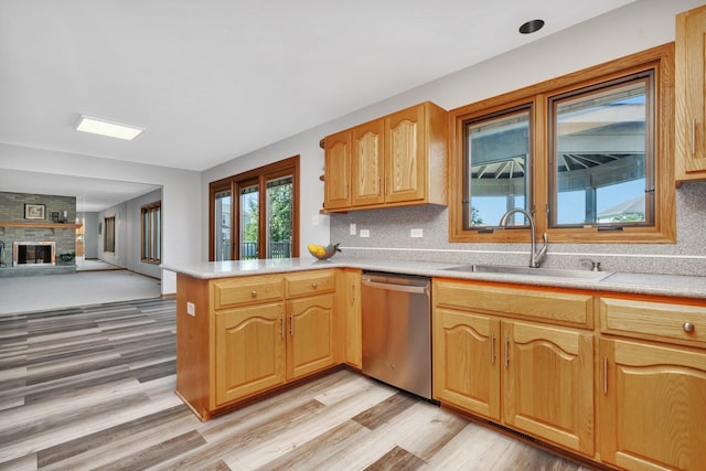 kitchen featuring sink, dishwasher, tasteful backsplash, a fireplace, and kitchen peninsula