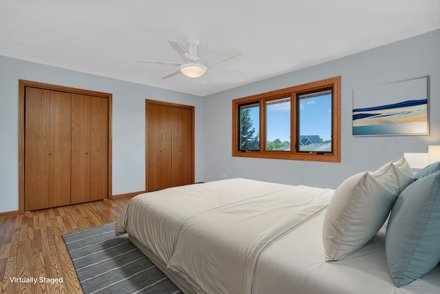 bedroom with two closets, ceiling fan, and light hardwood / wood-style flooring