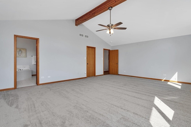 interior space featuring light colored carpet, beam ceiling, high vaulted ceiling, and ensuite bath