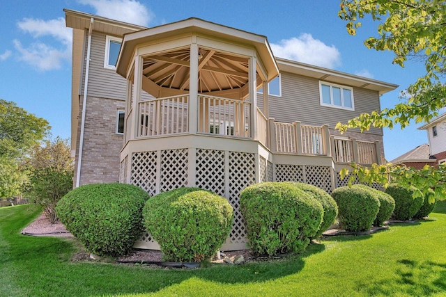 back of property featuring a wooden deck and a lawn