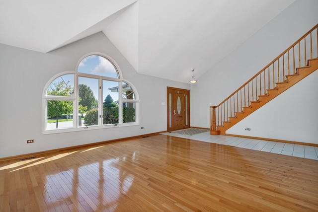 entryway with plenty of natural light, high vaulted ceiling, and light hardwood / wood-style floors