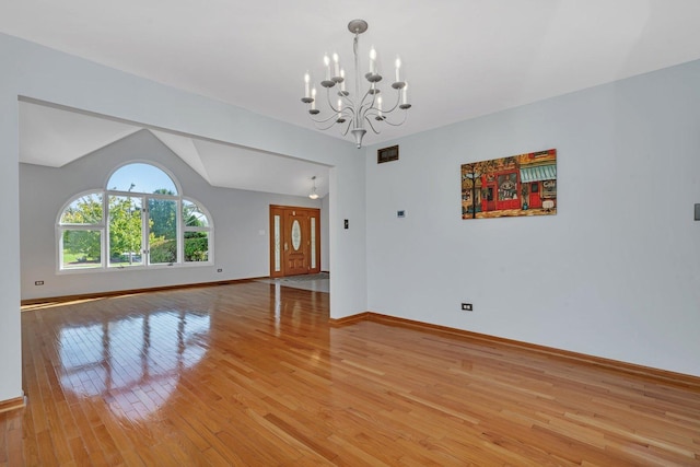 interior space featuring an inviting chandelier, vaulted ceiling, and light hardwood / wood-style floors