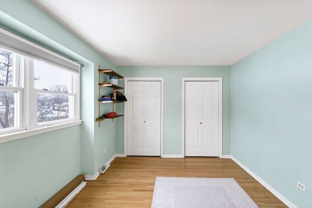 unfurnished bedroom with multiple closets and light hardwood / wood-style floors