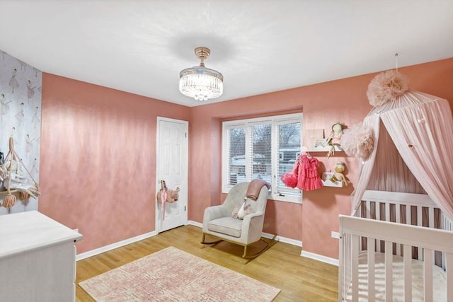 bedroom with hardwood / wood-style flooring, a crib, and a chandelier