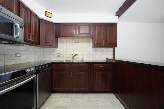 kitchen with appliances with stainless steel finishes, sink, dark stone countertops, and decorative backsplash