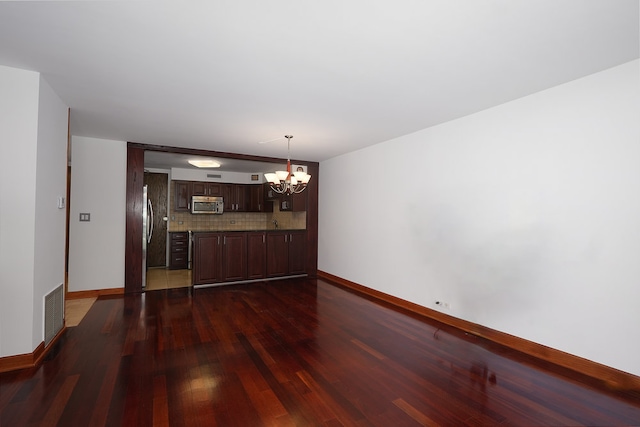 unfurnished dining area with dark wood-type flooring and a notable chandelier