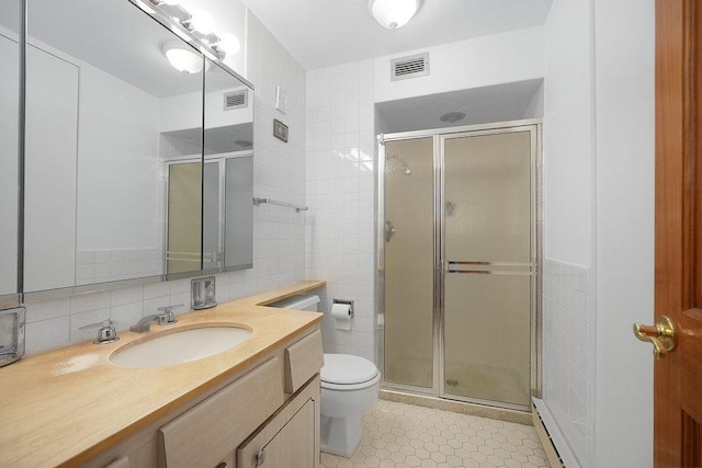 bathroom featuring a shower with door, tile walls, vanity, tasteful backsplash, and toilet