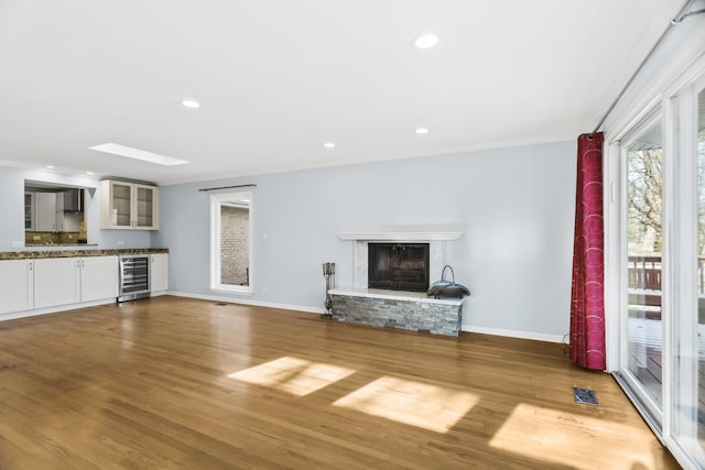 unfurnished living room featuring hardwood / wood-style floors, wine cooler, and a skylight