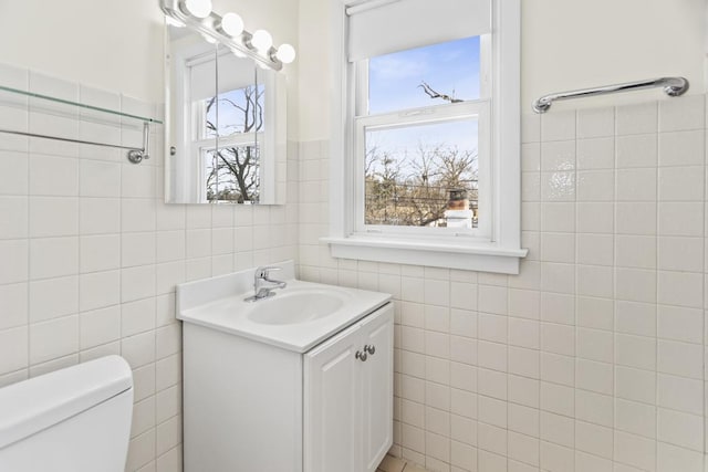 bathroom with vanity, toilet, and tile walls