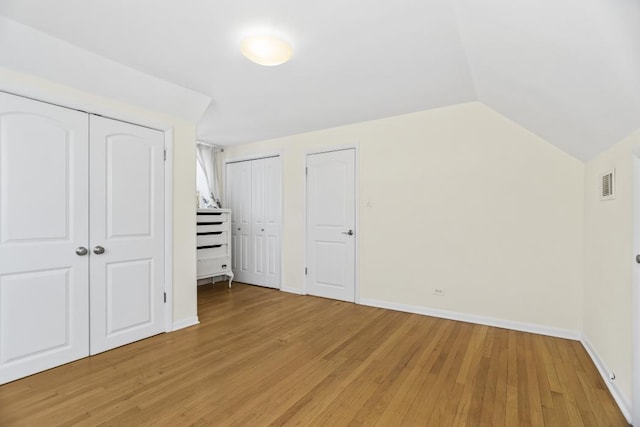 additional living space with vaulted ceiling and light hardwood / wood-style flooring