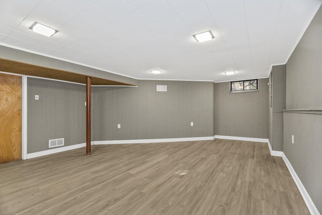 basement with wood-type flooring and crown molding