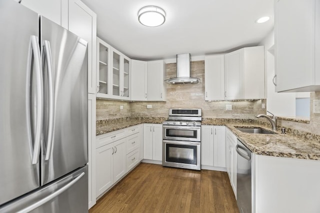 kitchen featuring sink, white cabinetry, stainless steel appliances, light stone countertops, and wall chimney range hood