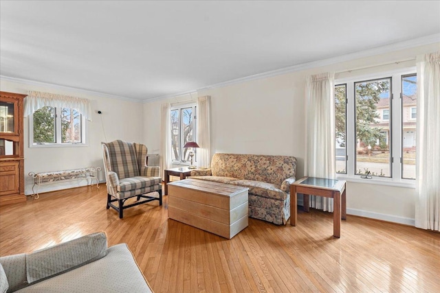 living room featuring plenty of natural light, ornamental molding, and light wood-type flooring