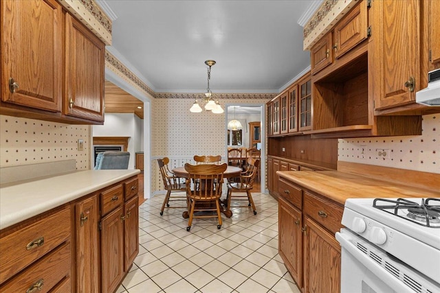 kitchen with gas range gas stove, crown molding, a chandelier, hanging light fixtures, and light tile patterned floors