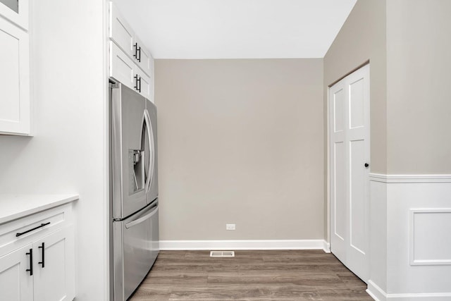 kitchen with hardwood / wood-style flooring, white cabinets, and stainless steel refrigerator with ice dispenser