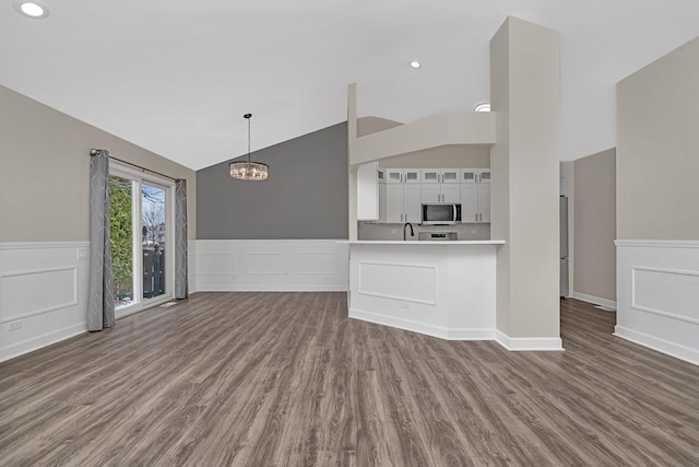 unfurnished living room with lofted ceiling, sink, dark hardwood / wood-style floors, and a chandelier