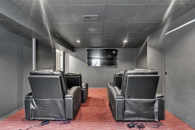 carpeted cinema room with a drop ceiling