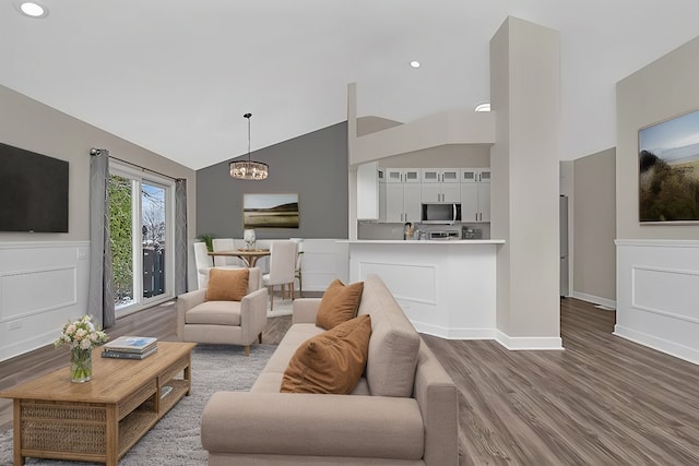 living room with hardwood / wood-style flooring, lofted ceiling, and an inviting chandelier