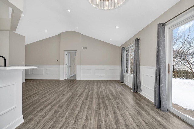 unfurnished living room featuring vaulted ceiling and dark hardwood / wood-style flooring