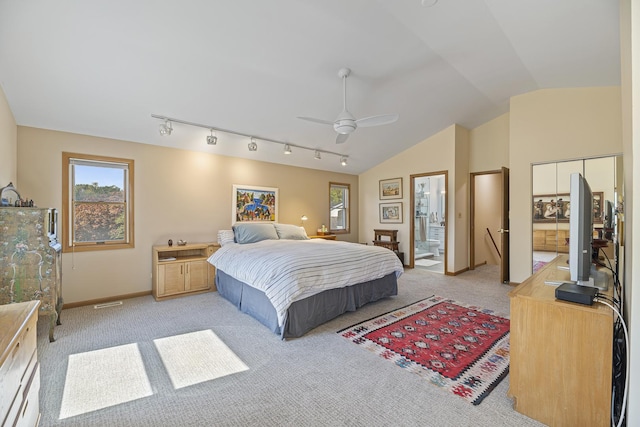 bedroom with vaulted ceiling, ensuite bathroom, track lighting, ceiling fan, and light carpet