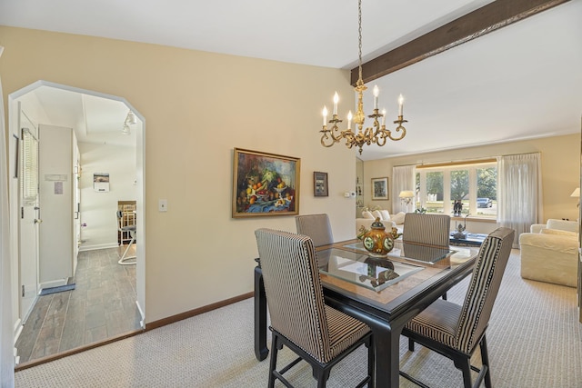 dining area featuring vaulted ceiling with beams and a chandelier