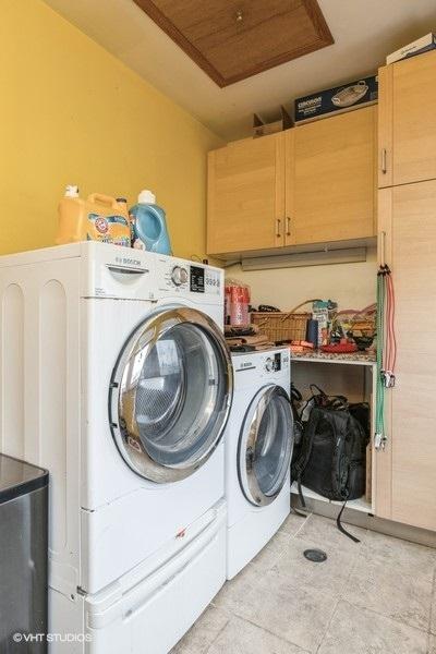 laundry area featuring cabinets, washer and dryer, and light tile patterned floors