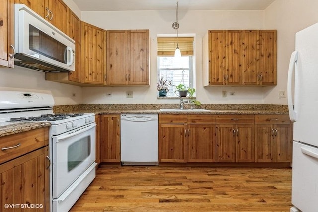 kitchen with sink, pendant lighting, white appliances, and light hardwood / wood-style flooring