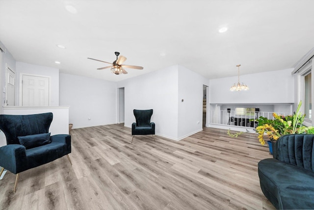 sitting room featuring ceiling fan with notable chandelier and light hardwood / wood-style floors