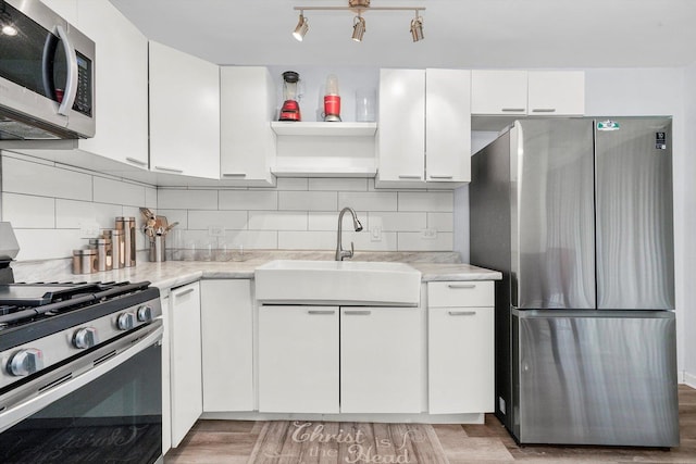 kitchen featuring sink, decorative backsplash, white cabinets, and appliances with stainless steel finishes