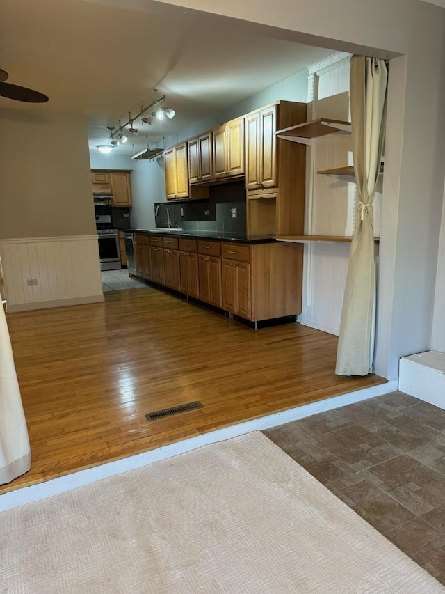 kitchen with wood-type flooring, track lighting, and stainless steel range with electric cooktop