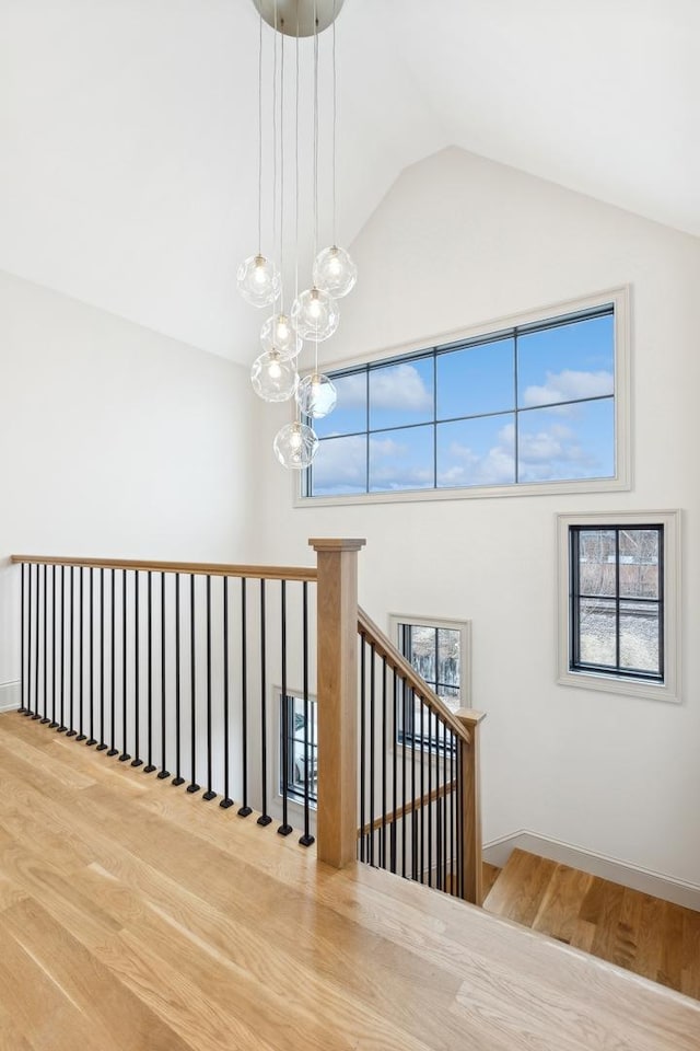 stairs featuring a wealth of natural light, wood-type flooring, and high vaulted ceiling