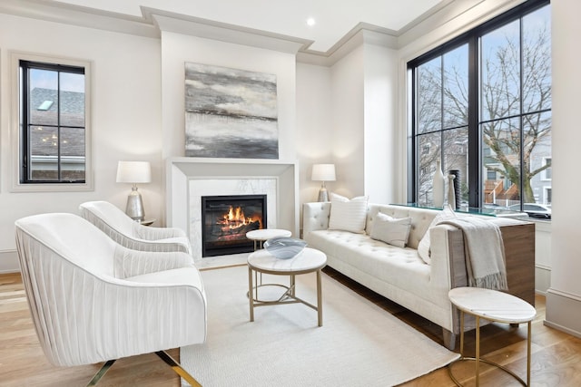 living room featuring crown molding, a fireplace, and light wood-type flooring