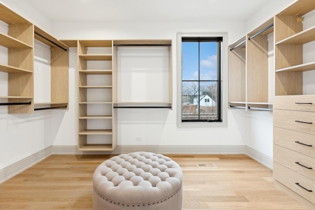 walk in closet with light hardwood / wood-style floors