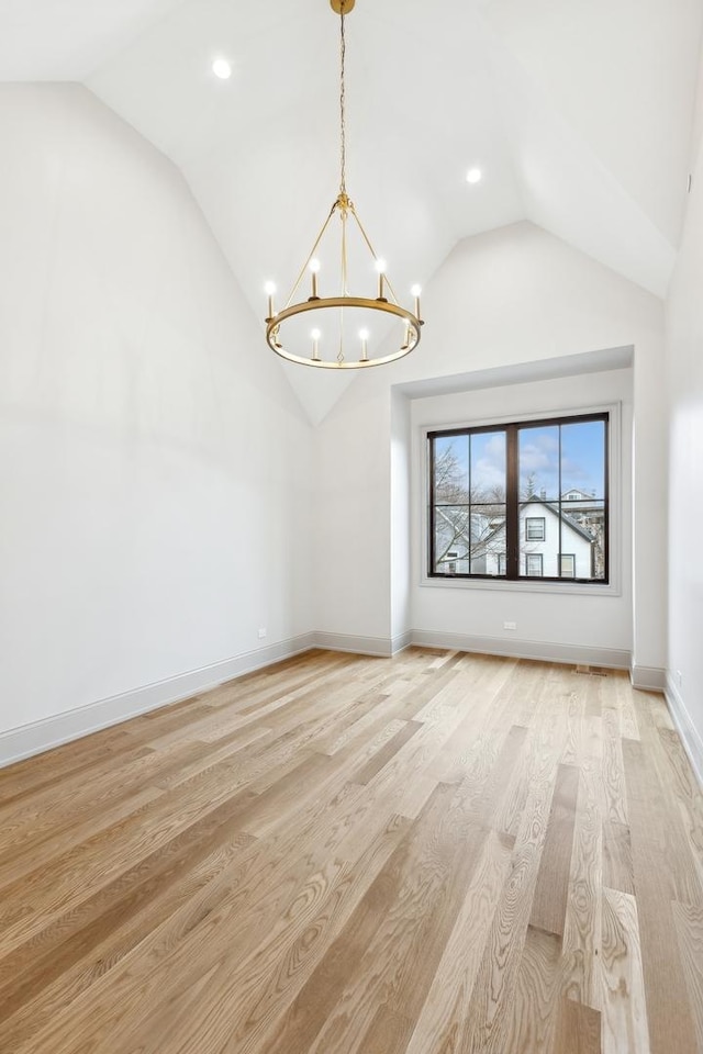 interior space featuring light wood-type flooring, vaulted ceiling, and a notable chandelier