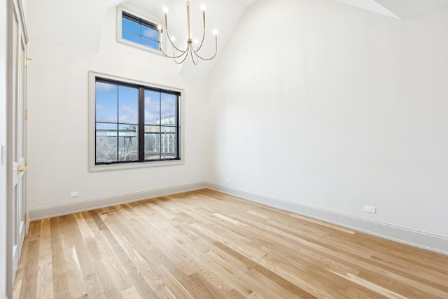 spare room featuring an inviting chandelier, high vaulted ceiling, light hardwood / wood-style flooring, and a wealth of natural light