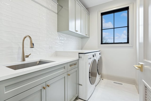 laundry area with independent washer and dryer, cabinets, and sink