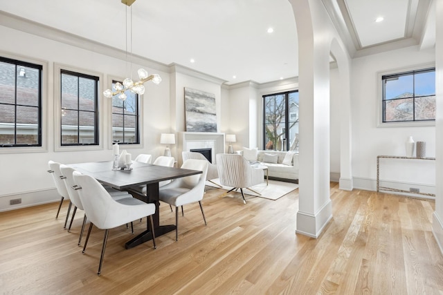 dining area featuring a notable chandelier, ornamental molding, and light wood-type flooring