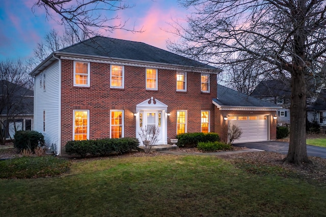 colonial home with brick siding, a lawn, driveway, and a garage