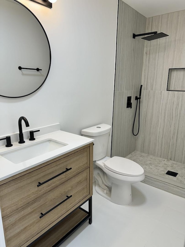 bathroom featuring tiled shower, vanity, and toilet