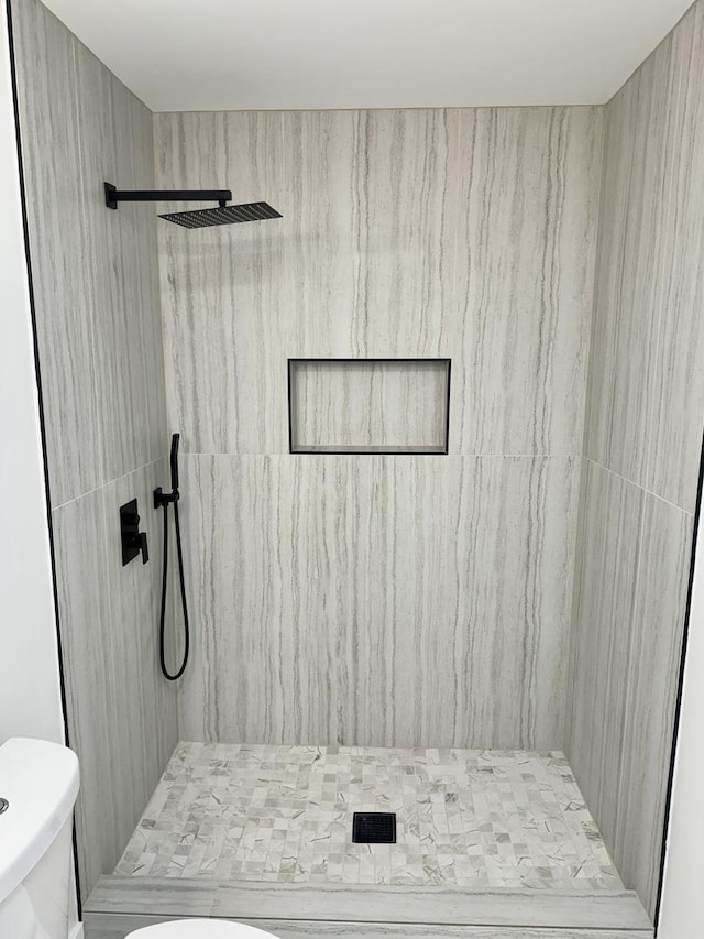 bathroom featuring a tile shower and toilet