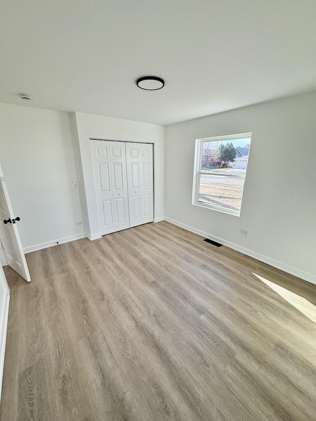 unfurnished bedroom featuring light hardwood / wood-style flooring and a closet