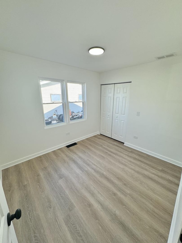 unfurnished bedroom featuring light hardwood / wood-style floors and a closet