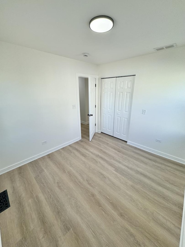 unfurnished bedroom featuring light hardwood / wood-style floors and a closet