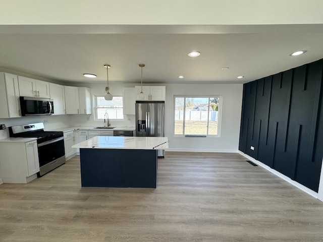 kitchen featuring a kitchen island, pendant lighting, sink, white cabinets, and stainless steel appliances